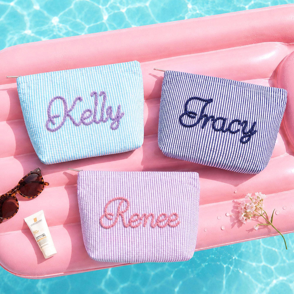 Personalized seersucker makeup bags embroidered with custom names by the pool