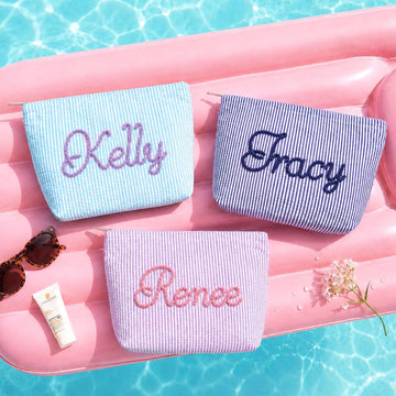 Personalized seersucker makeup bags embroidered with custom names by the pool